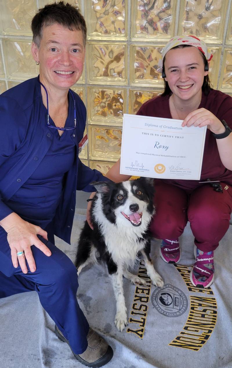 two women holding a certificate and a dog